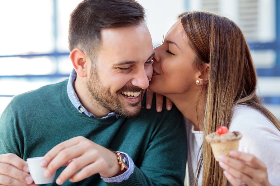 pareja feliz comiendo helado y dándose un beso en la mejilla