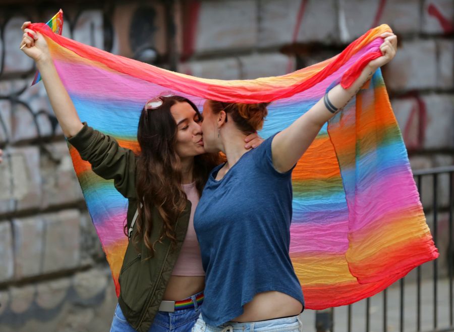 pareja mujeres lesbianas besándose bajo la bandera lgbt